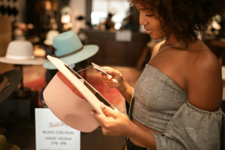 A fashionable woman examines a hat price tag in a chic boutique setting.